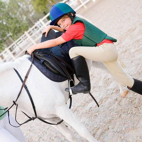 a girl in a helmet and riding gear on a white horse